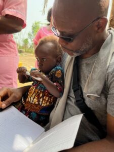 Lamin Foray, Board Member, at with child being treated at Mobile Outreach Clinic